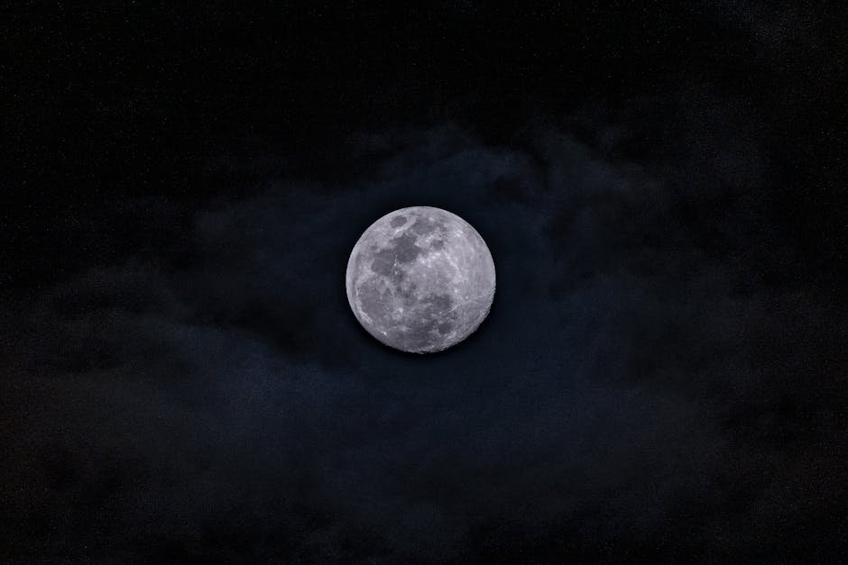 Beautiful full moon illuminating the dark night sky with surrounding clouds, perfect for nighttime themes.